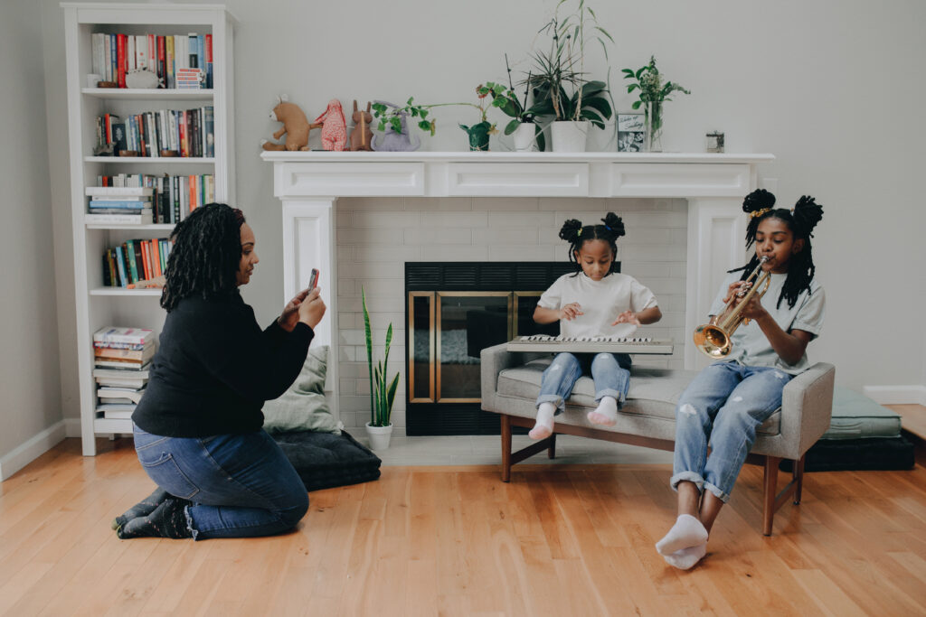 A mother taking photos of her kids while playing musical instruments