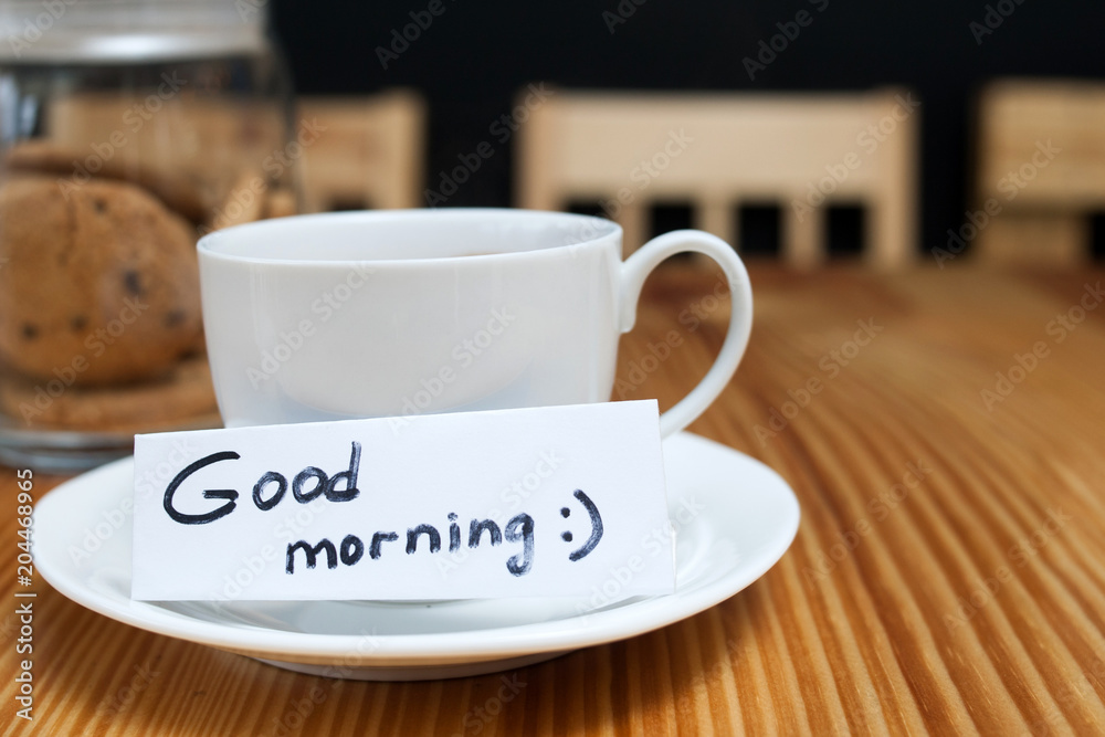breakfast ritual of coffee and biscuits. white cup with a wishing of good morning on the wooden table